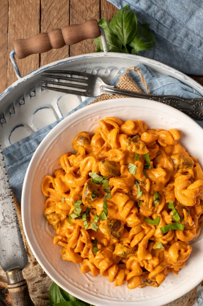 creamy roasted red pepper pasta in white bowl on tray