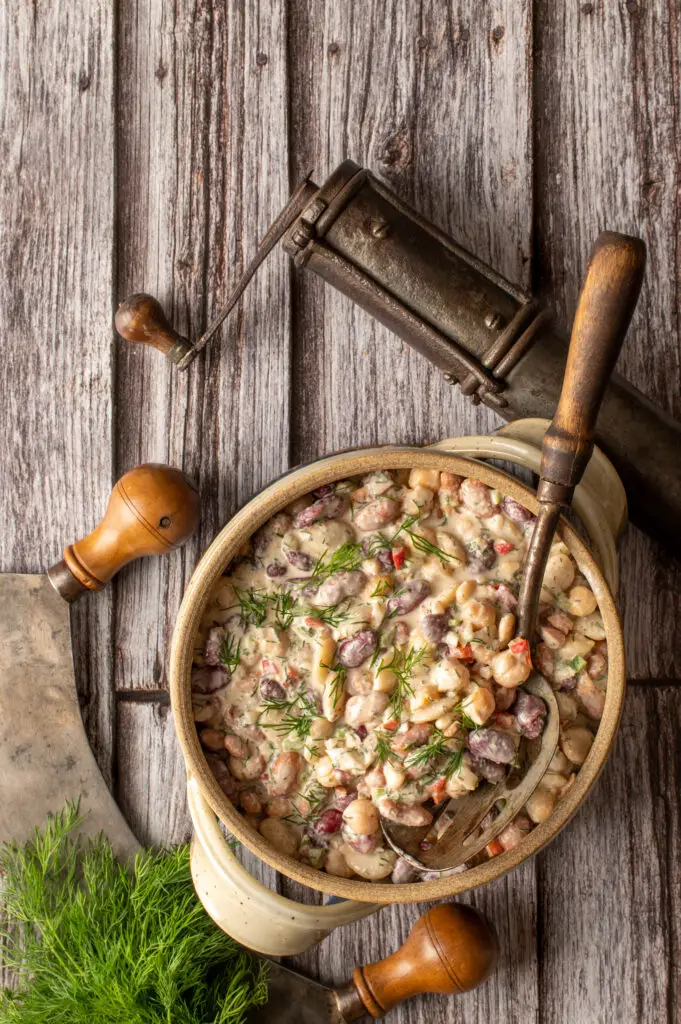 middle eastern bean salad in pottery crock next to spice grinder and herb chopper