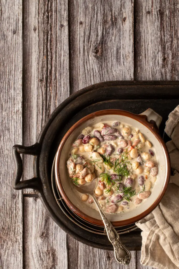 middle eastern bean salad in pottery bowl on iron tray