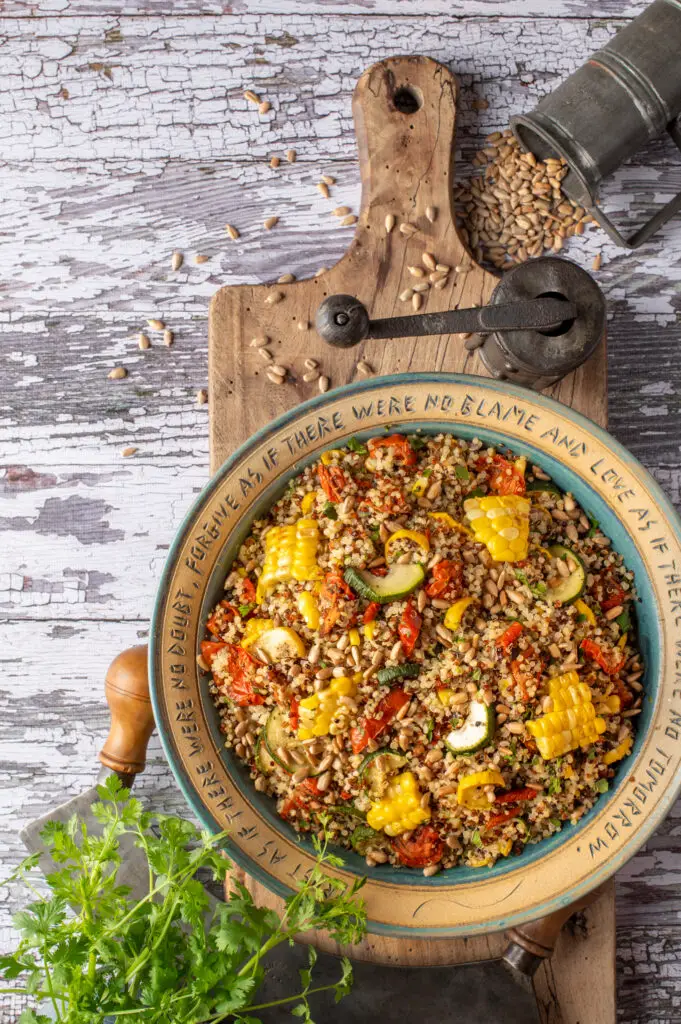 quinoa with summer vegetables in pottery bowl on cutting board