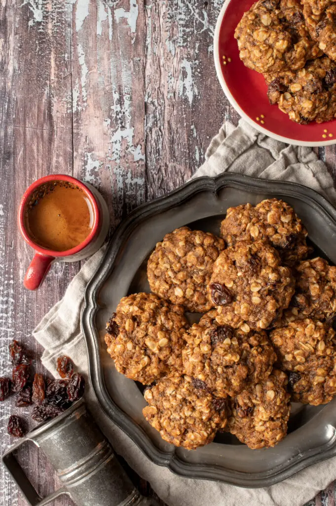 vegan oatmeal raisin cookies on pewter plate next to cup of espresso