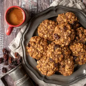 vegan oatmeal raisin cookies on pewter plate next to cup of espresso - recipe image