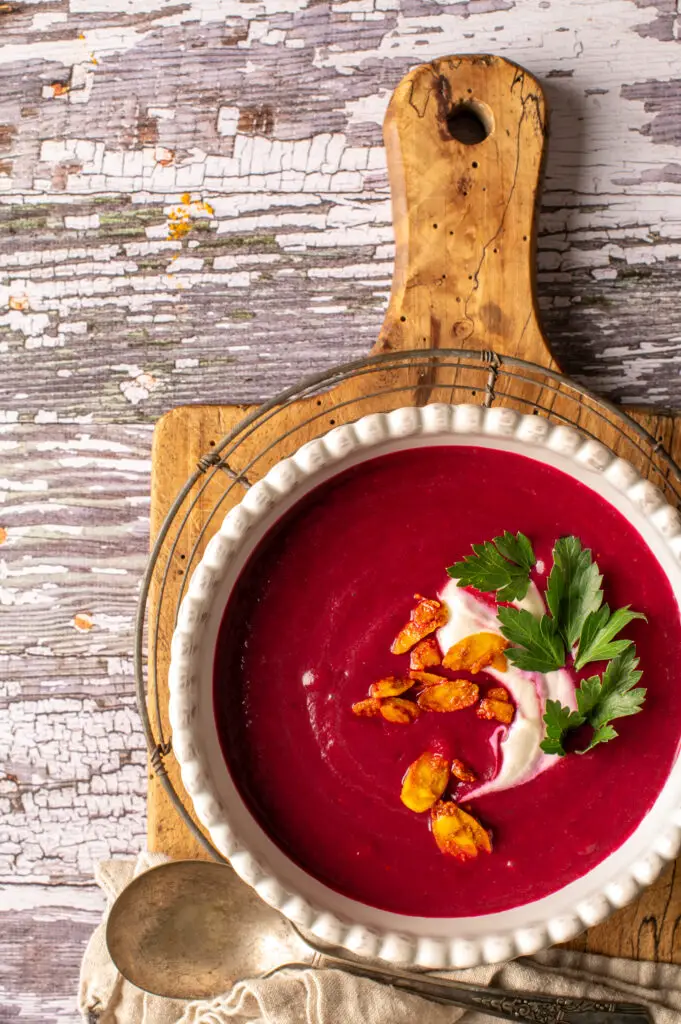 velvety beet soup in white bowl sitting on cutting board